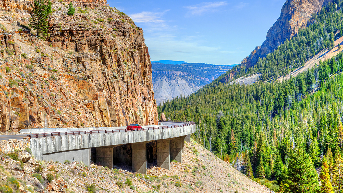 Red car on Grand Loop Road through Golden Gate Canyon at Kingman Pass in the northwestern region of Yellowstone National Park, Wyoming, USA.