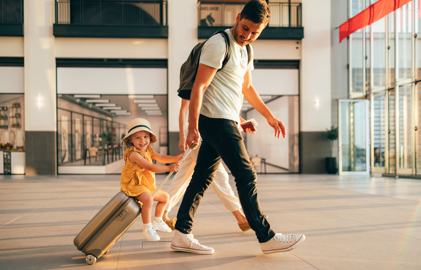 couple walking through airport with child riding on luggage