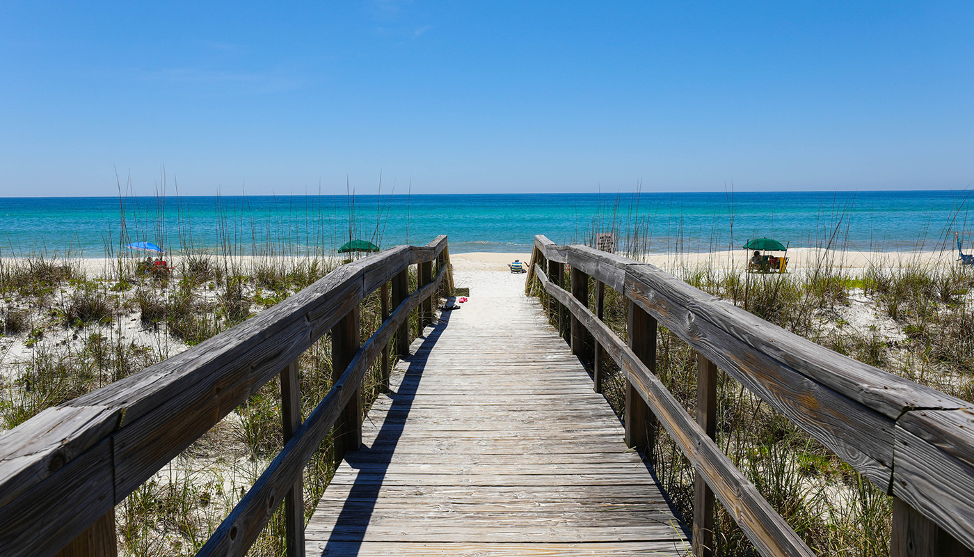 1442413677 Wooden walkway over sand dunes leading to an uncrowded beach