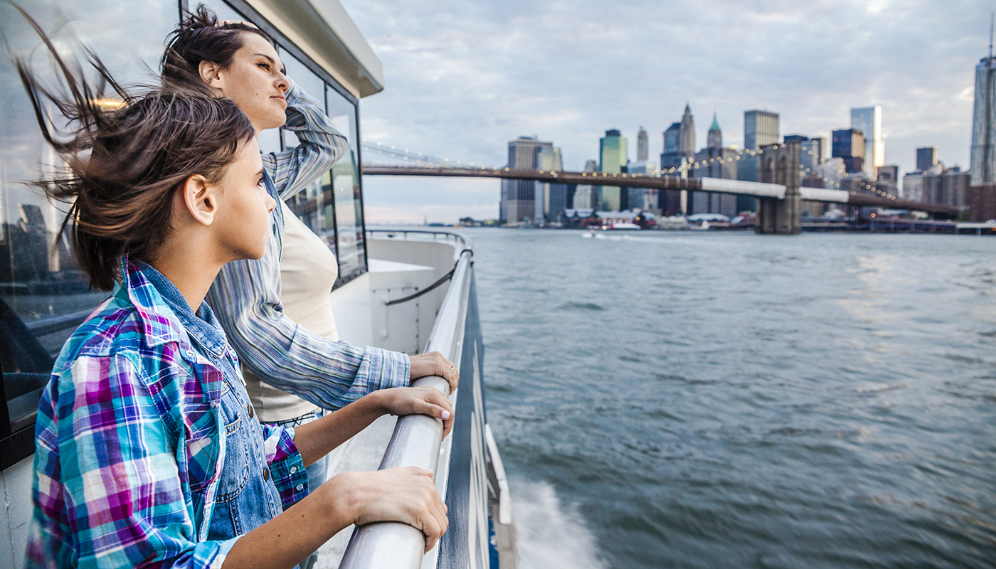 A woman and a girl take in the sight of a city from the ferry.