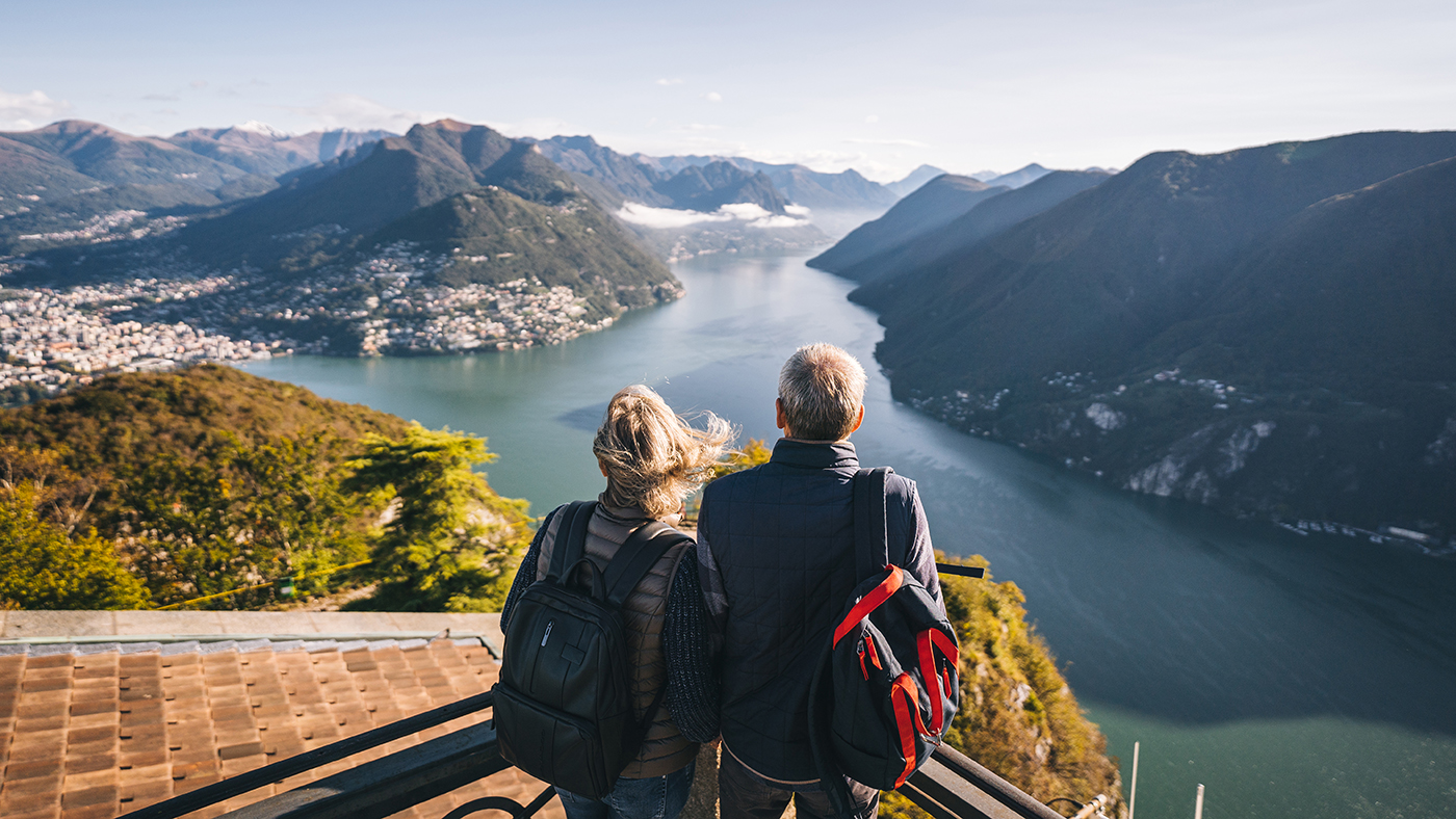 An older couple relax at viewpoint and look off to distant scene