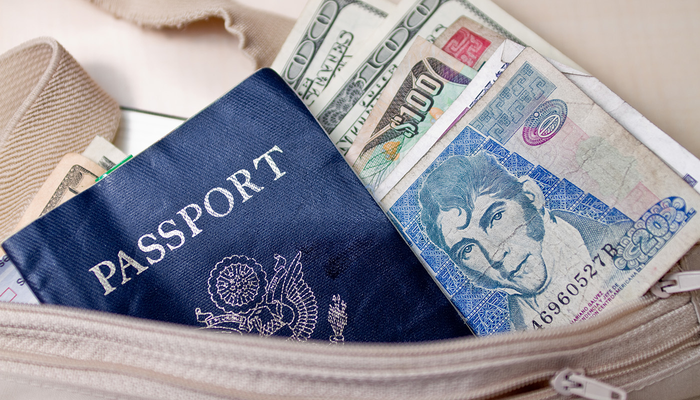 A passport and foreign currency stick out of the top of a travel bag.