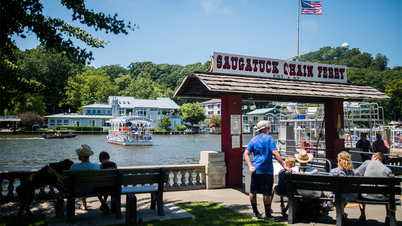 Onlookers watch the Saugatuck Chain Ferry escort visitors across a river in Michigan