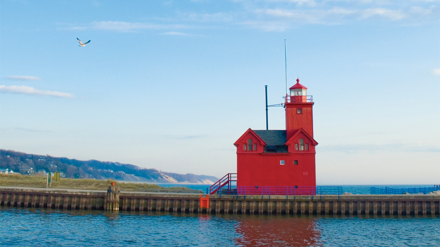 A red lighthouse sits at the entrance to a channel in Holland Harbor in Michigan