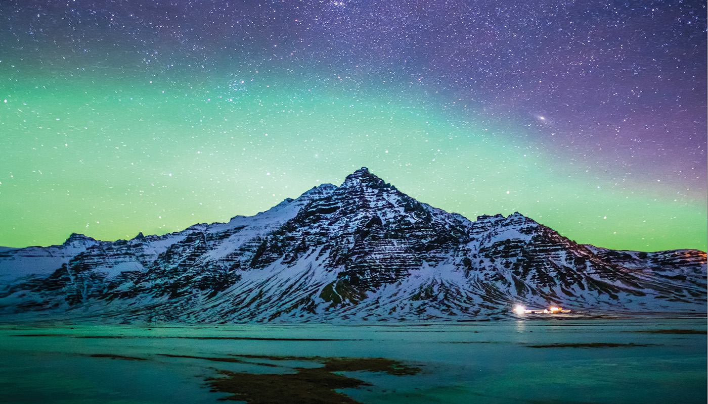Snowy mountain peak in southern Iceland with Northern Lights in sky above