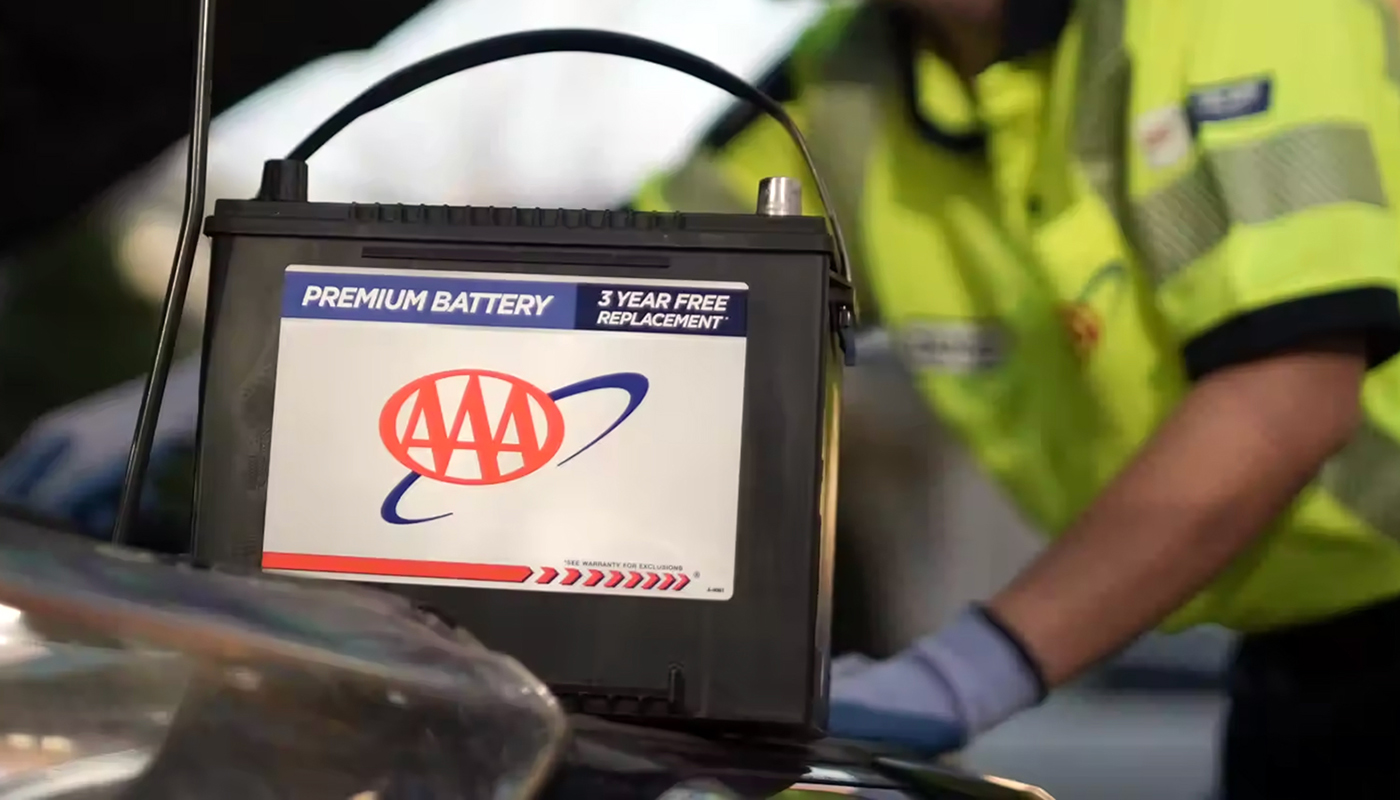 AAA mechanic puts a new battery into a vehicle.