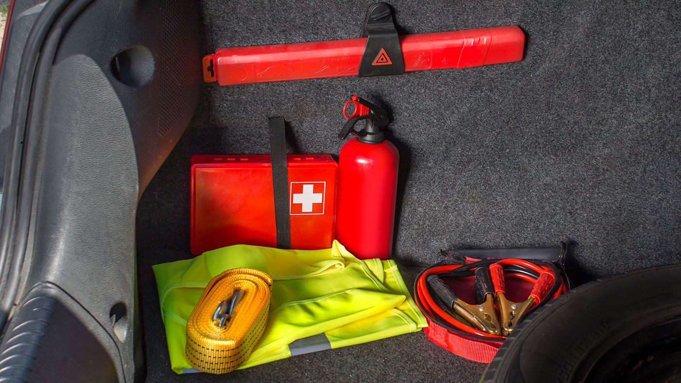A first aid kit and other tools for a road trip in the trunk of a car.