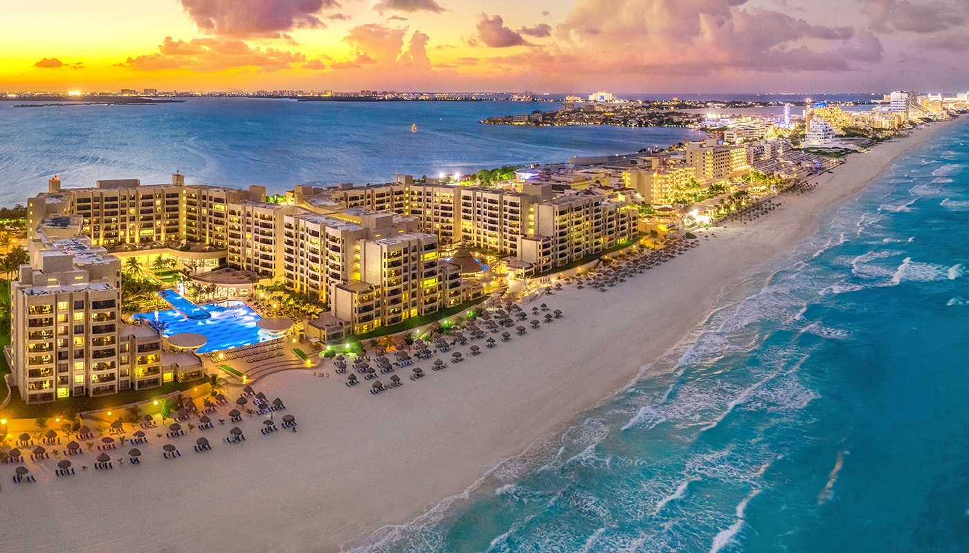 Aerial view of resort in Cancun surrounded by blue water at sunset