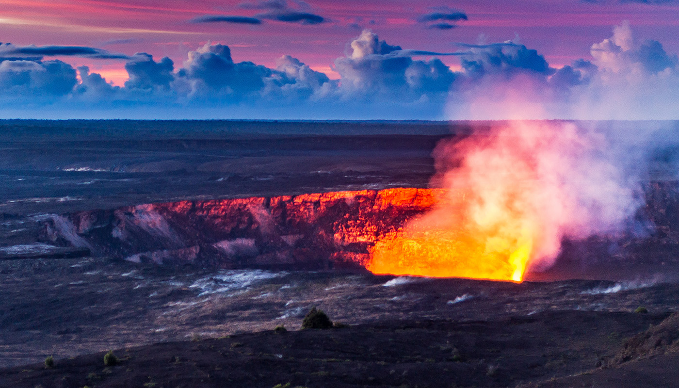 Dawn at the Lava Lake at Halema'uma'u. The top is bright orange and smoke drifts above.