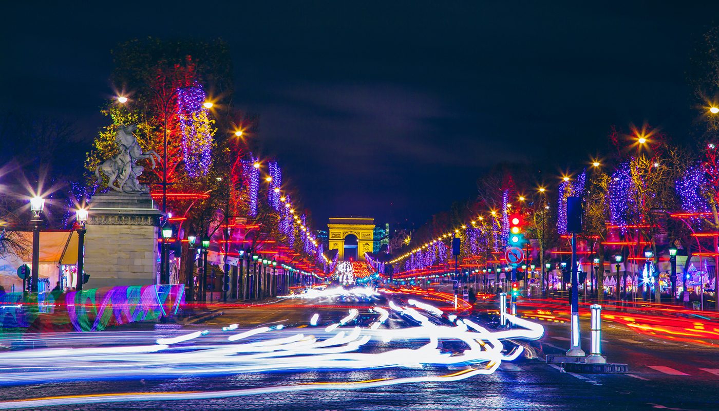 Motion blurred cars on Champs Élysées and Arc de Triomphe with Christmas city lights