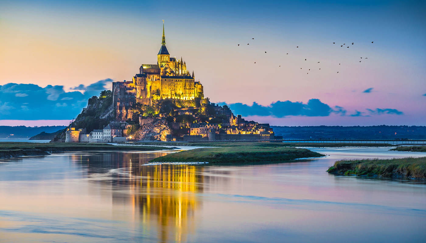 Beautiful view of famous Le Mont Saint-Michel tidal island in beautiful twilight during blue hour at dusk, Normandy, northern France.
