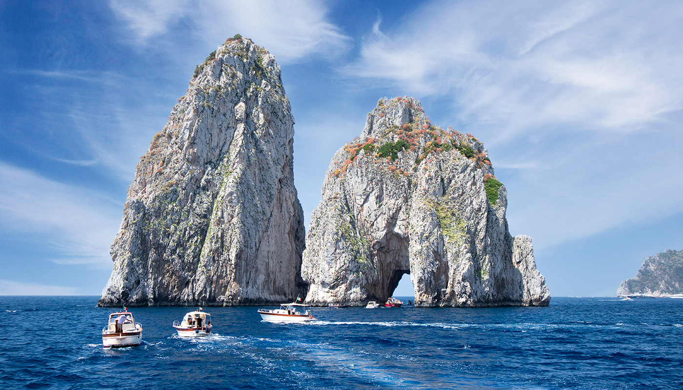 The Faraglioni Rocks tower over the water. 