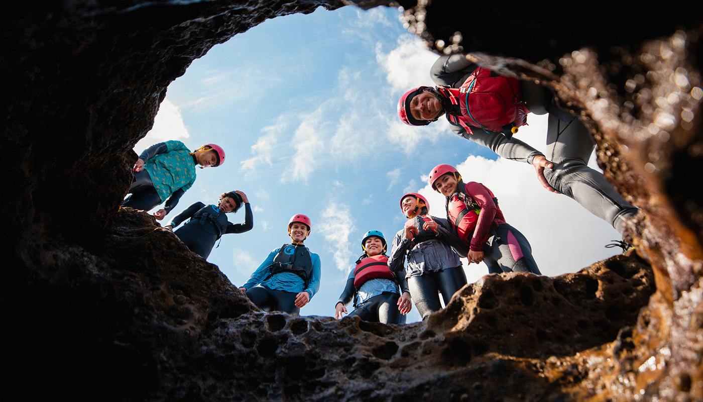 A view from inside a cave, looking up at a group of spelunkers