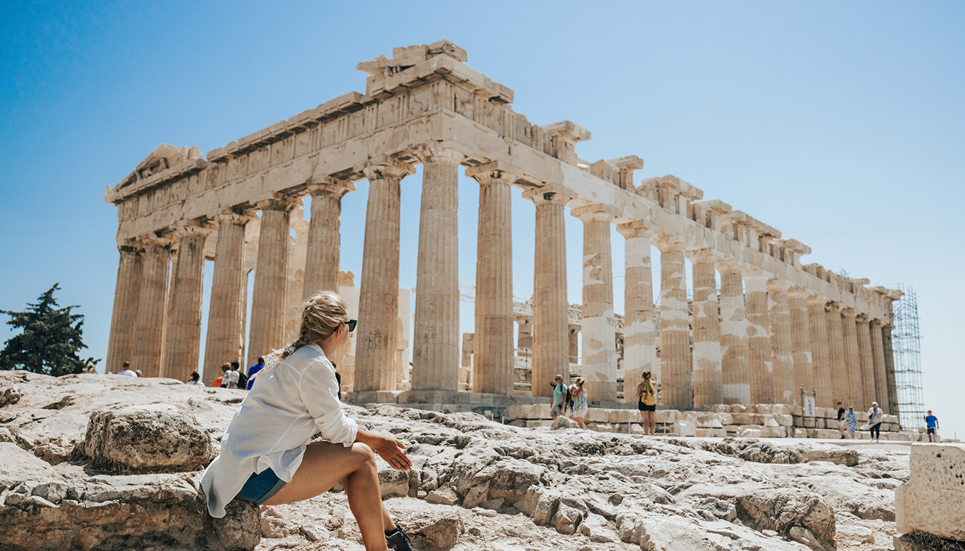 A traveler sits in front of the Acropolis in Athens.