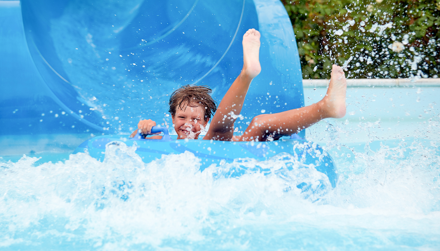 A boy smiles as he reaches the bottom of waterslide.