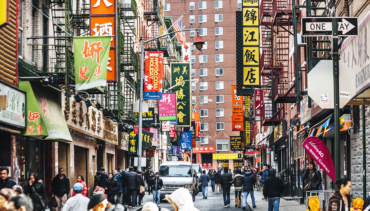 A large number of signs hang above a busy street in Chinatown. 