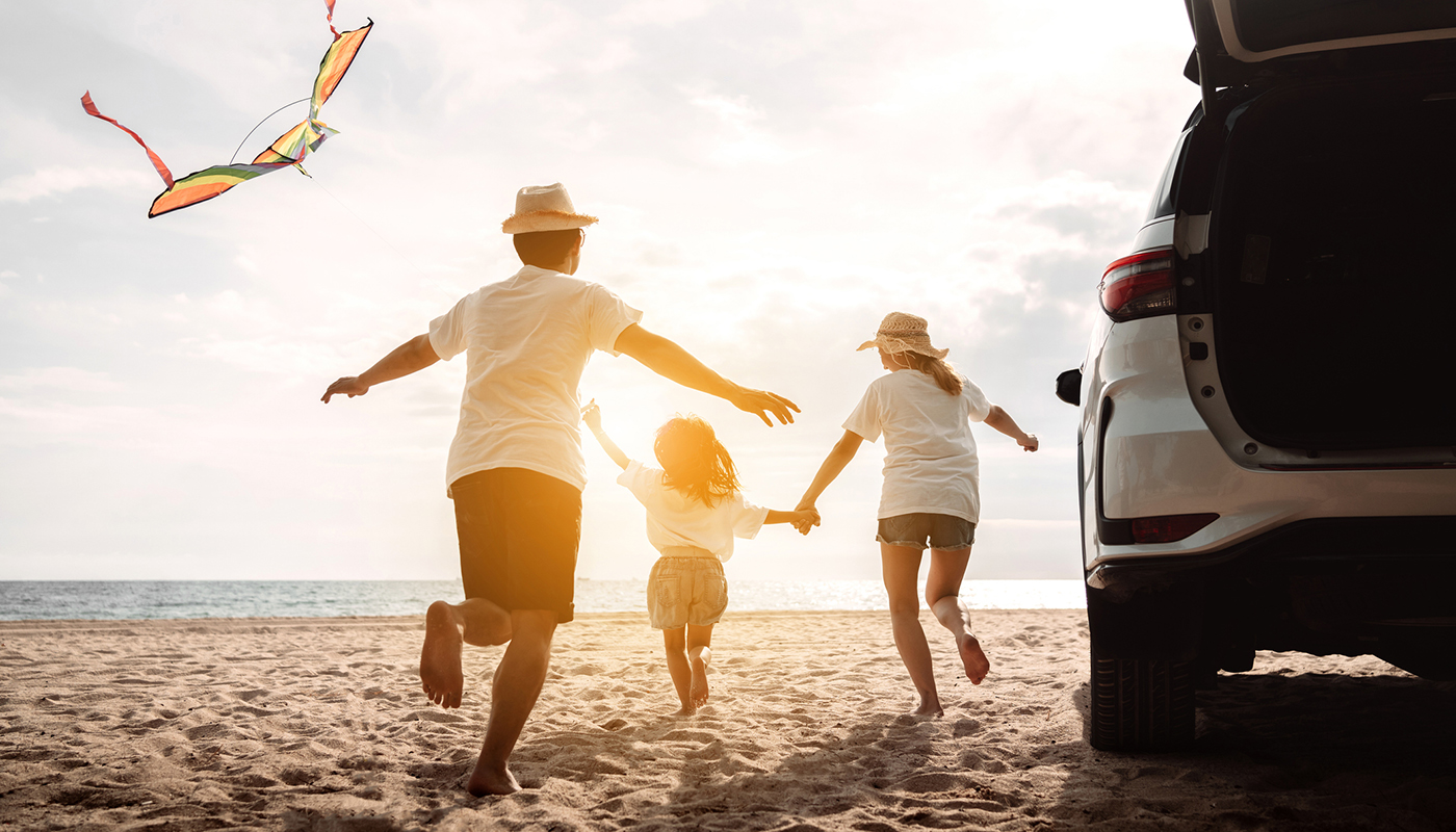 A family playfully runs along the beach on a sunny day