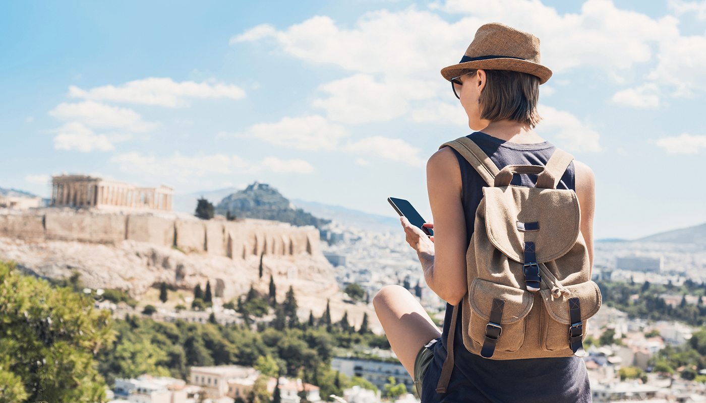 A woman wearing a backpack and sunglasses looks out toward the Colosseum in Rome