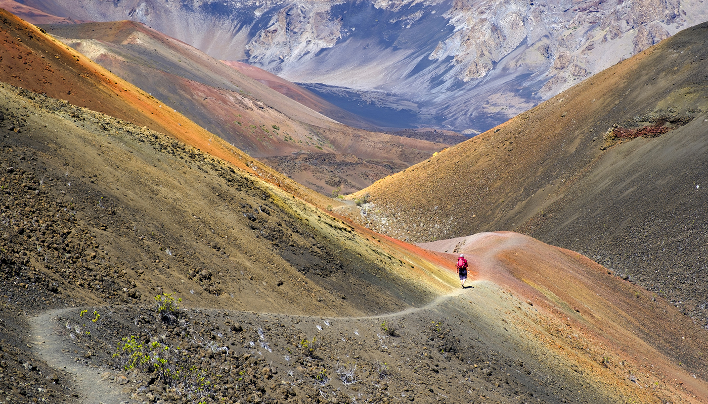 A hiker covers the trails of the hilly Hawaiian terrain of the dormant volcano, Haleakalā. 