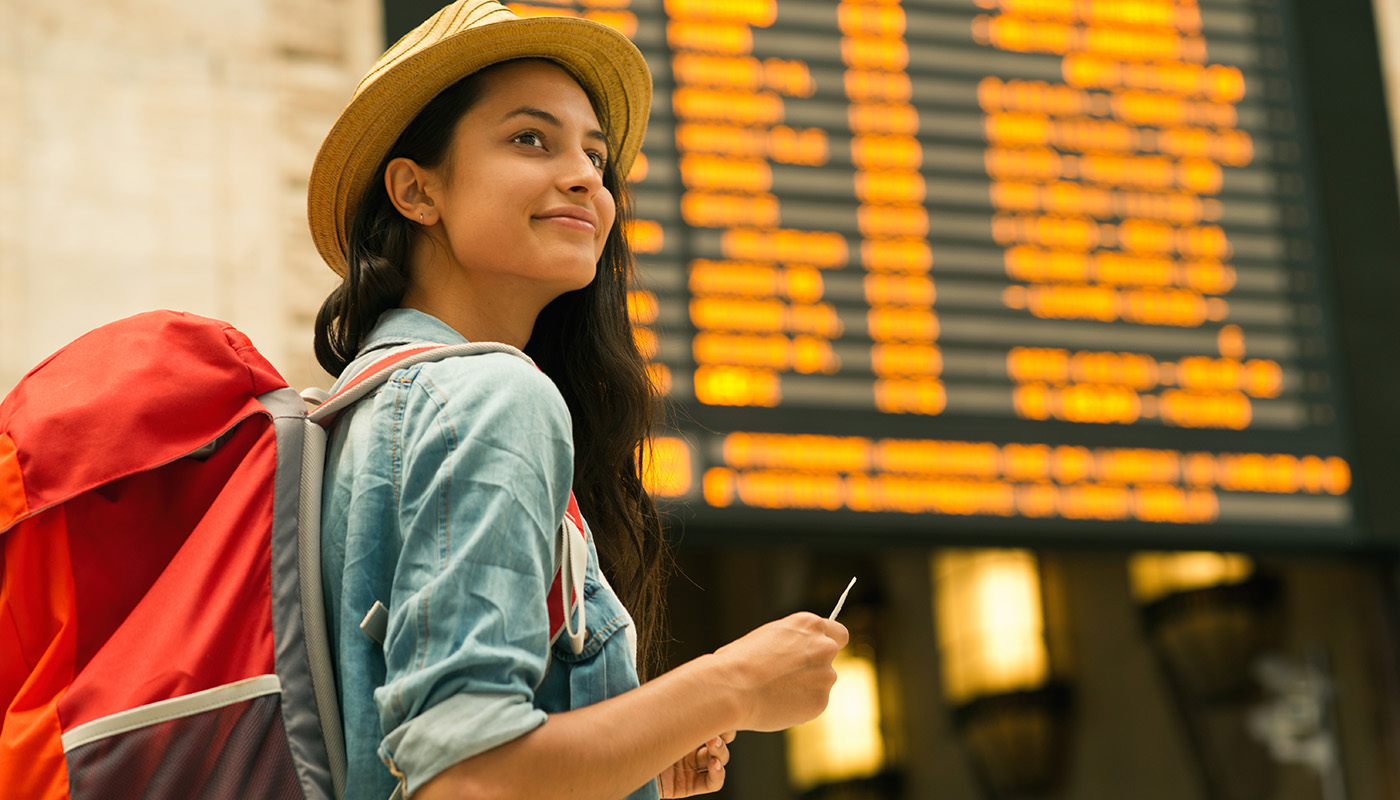 Female tourist with backpack checking the arrival and departure board in airport