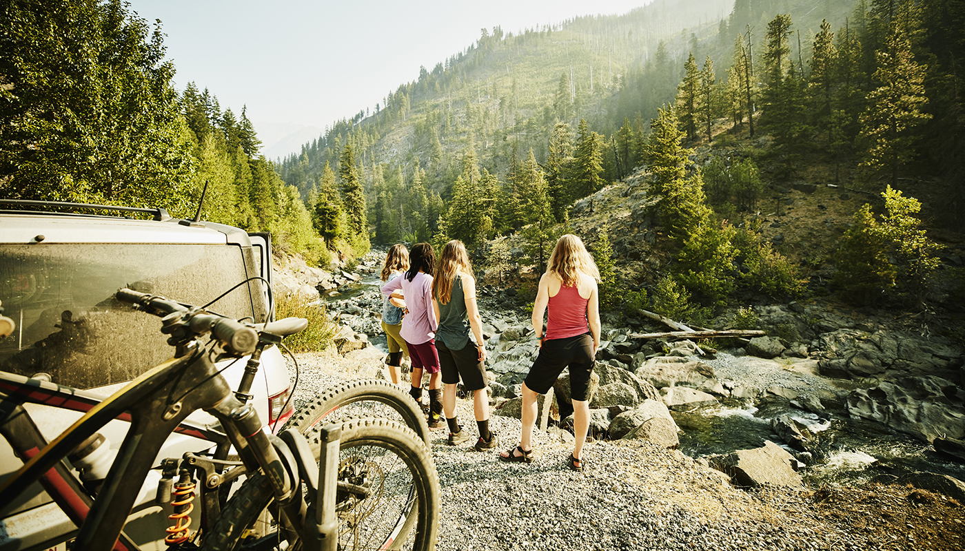 Group of friends standing at overlook with bikes mounted on vehicle in the foreground
