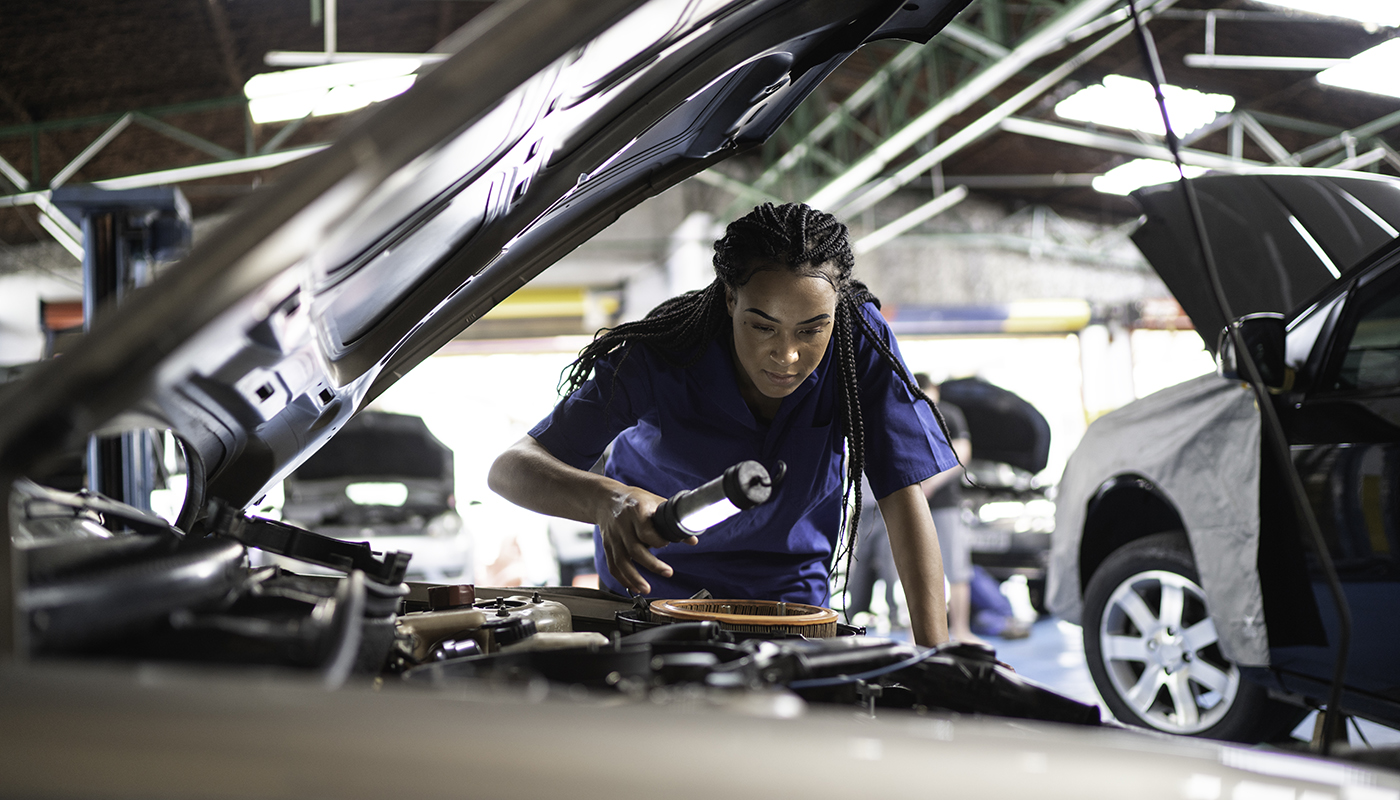 Woman mechanic working on a car in an auto repair shop