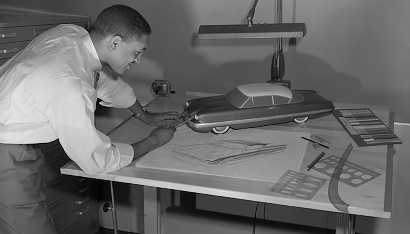 McKinley Thompson Jr. working on a concept drawing of a vehicle on a drafting table with various drafting tools