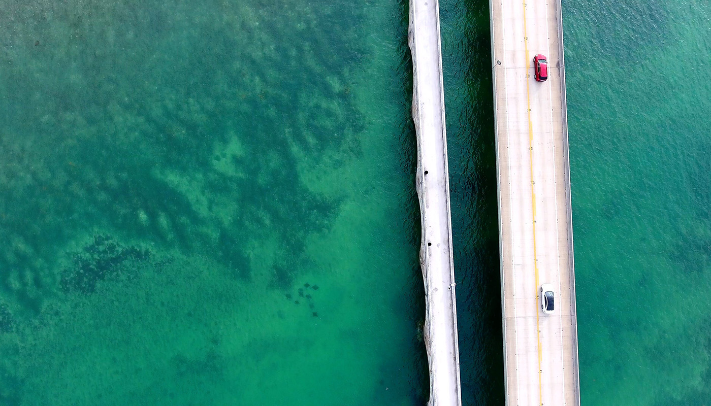 An aerial of cars driving on a bridge over the ocean in Florida