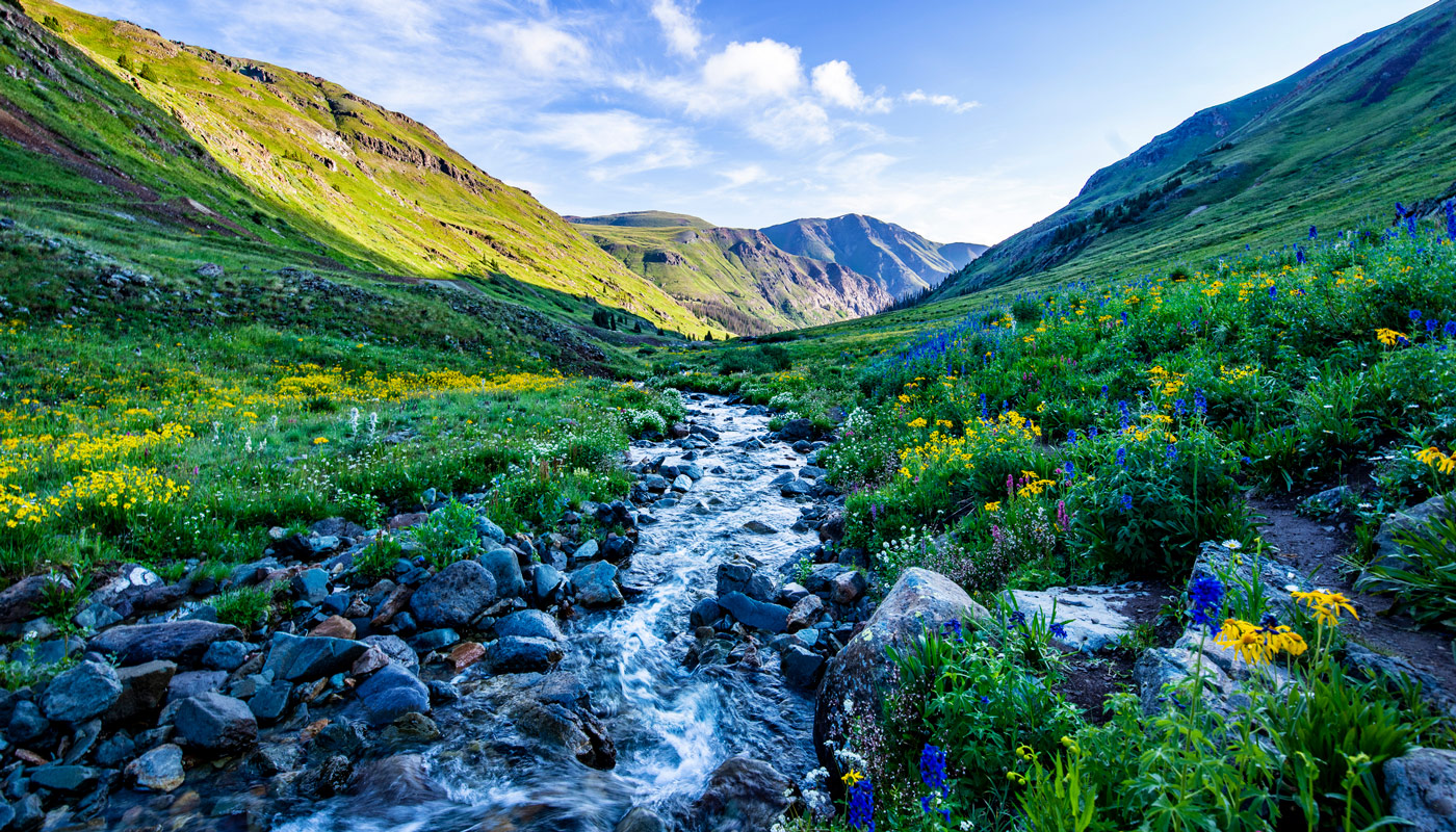 A Colorado mountainous range with a flowing creek as a symbol of how recycling can keep the environment clean.