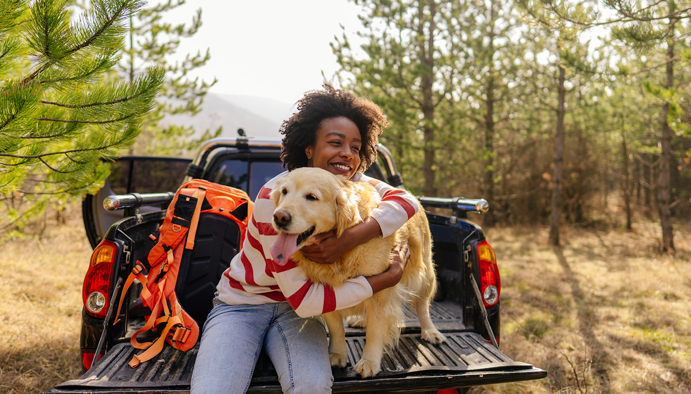 Young woman hugging her Golden Retriever in the back of her pickup truck