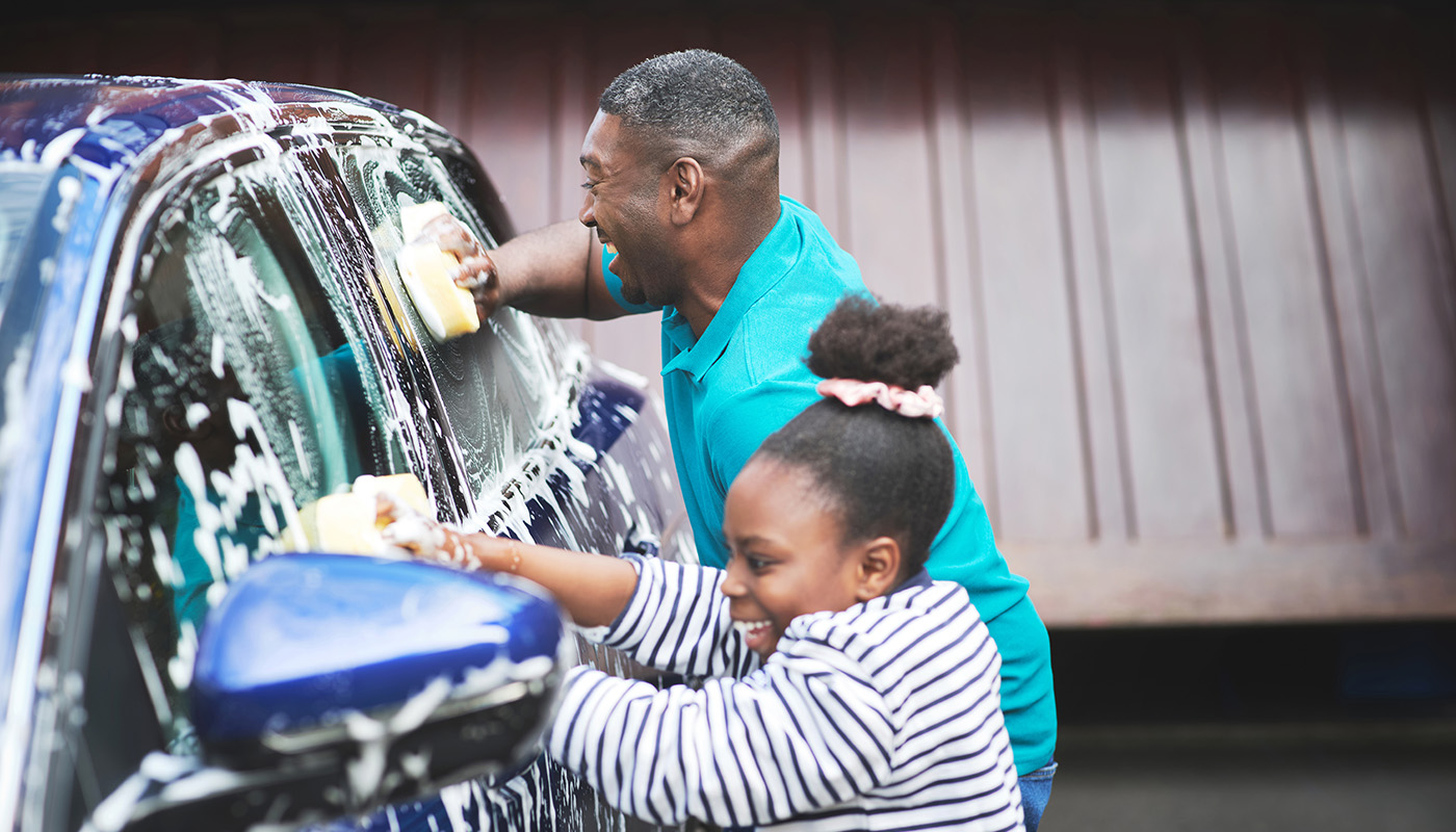 Father and daughter washing car outside