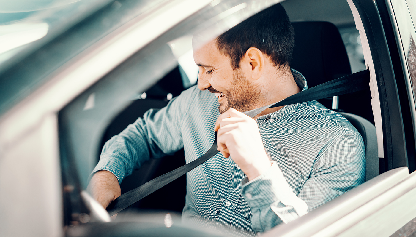 Man fastening seat belt in car