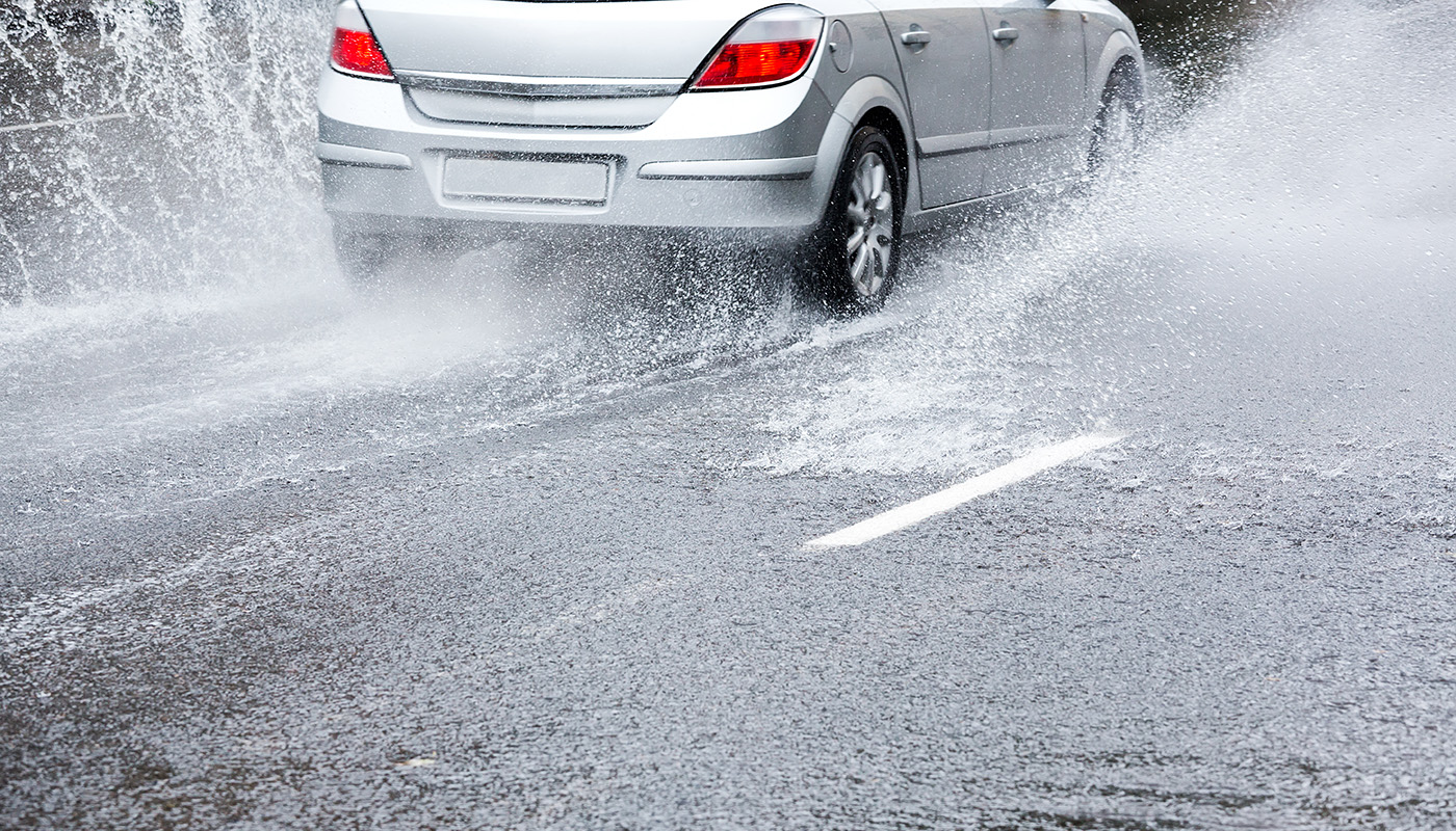Car driving on wet road, splashing water to the side
