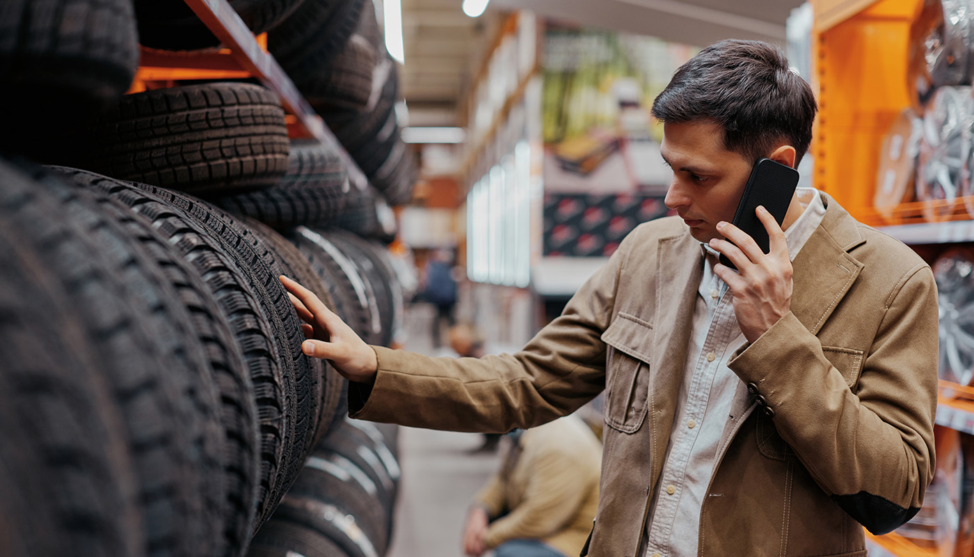 Man shopping for new tires in auto shop while talking on mobile phone