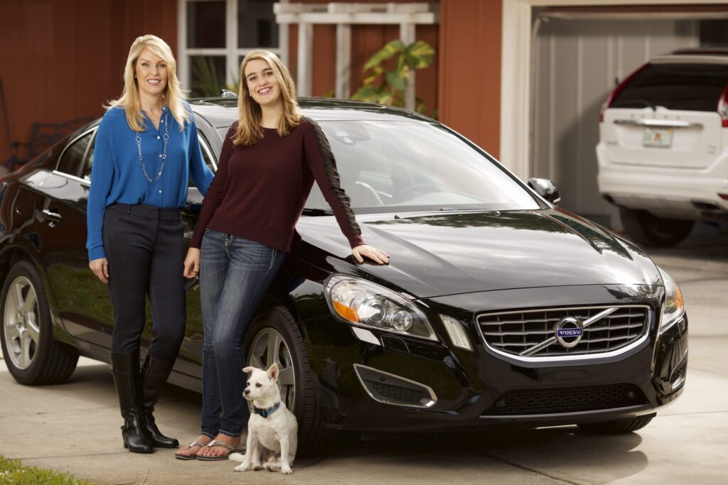 Mom and teenage daughter beside her first car.