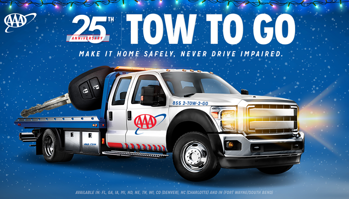 Conceptual AAA tow truck with car keys in the towing bed on a blue background with holiday lights