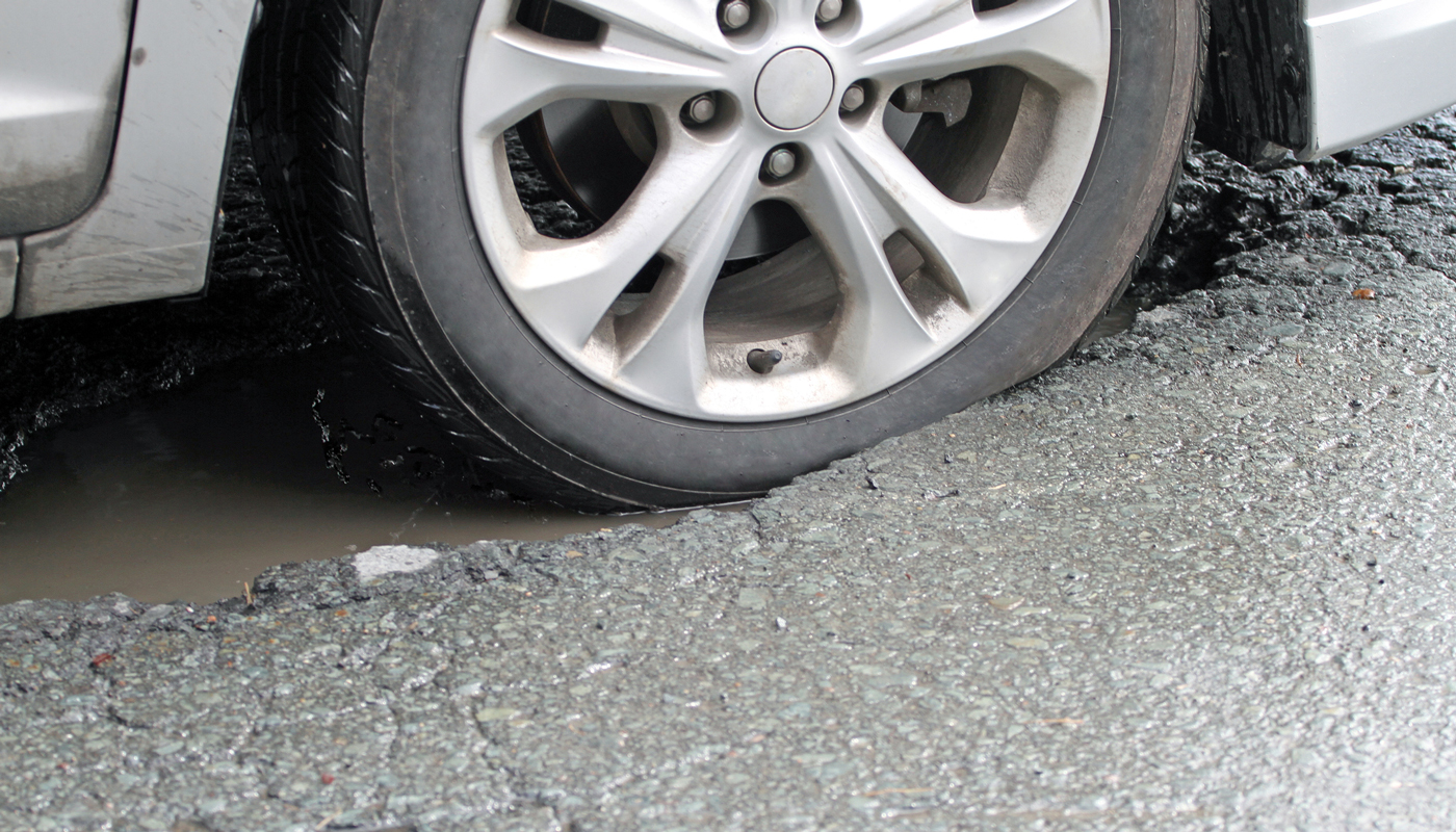 Car tire hitting a pothole in the road