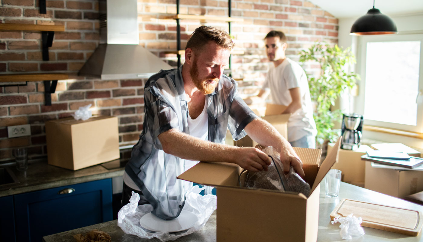 Young male gay couple unpacking boxes at new home