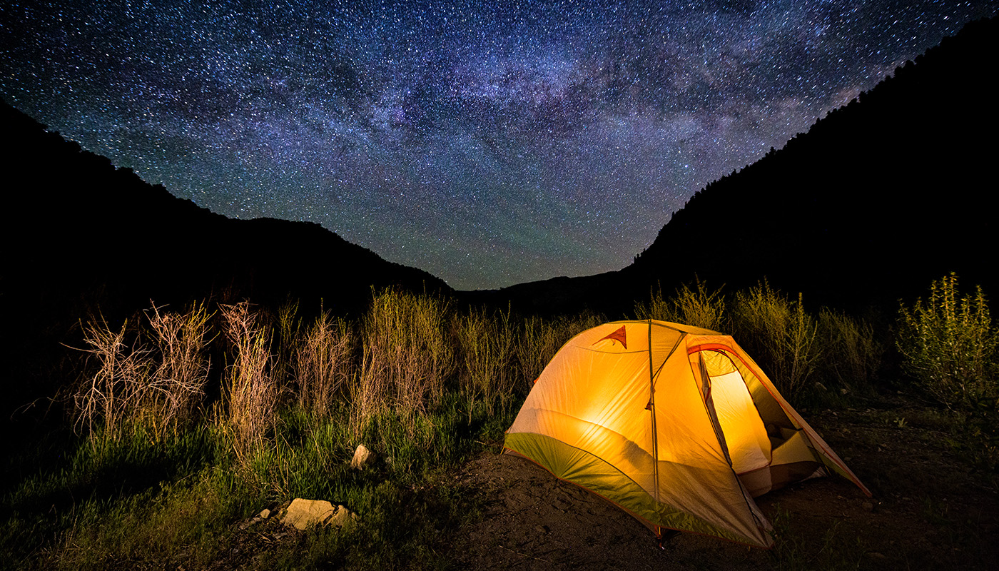 Tent at night with vast sky of stars in background
