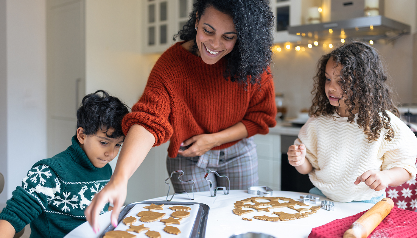 Sister and brother making Christmas gingerbread cookies with a mother