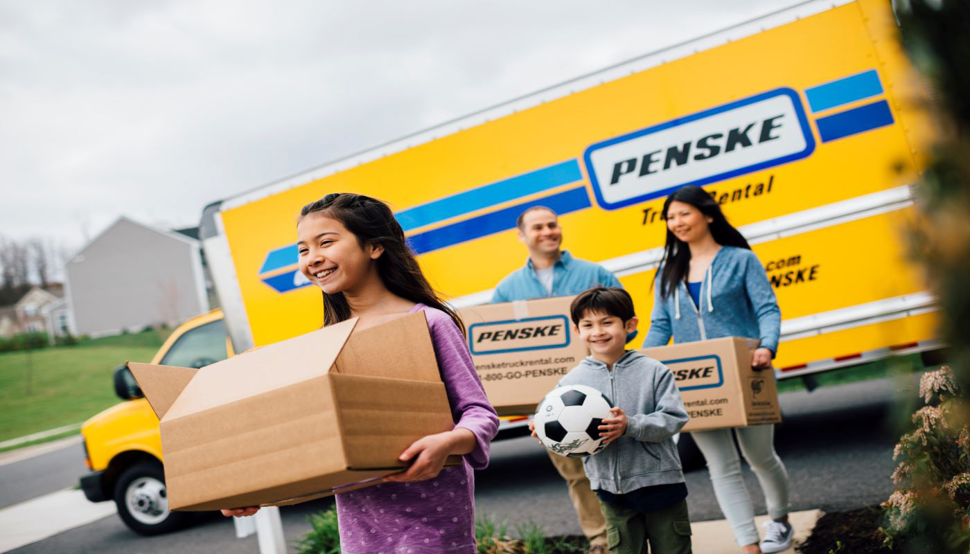 Family carrying moving boxes from Penske truck