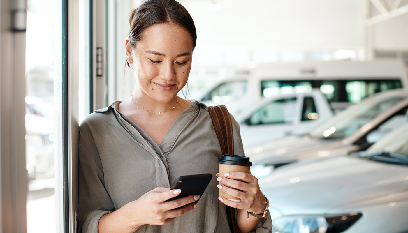 Woman looking at smartphone with row of cars in the background