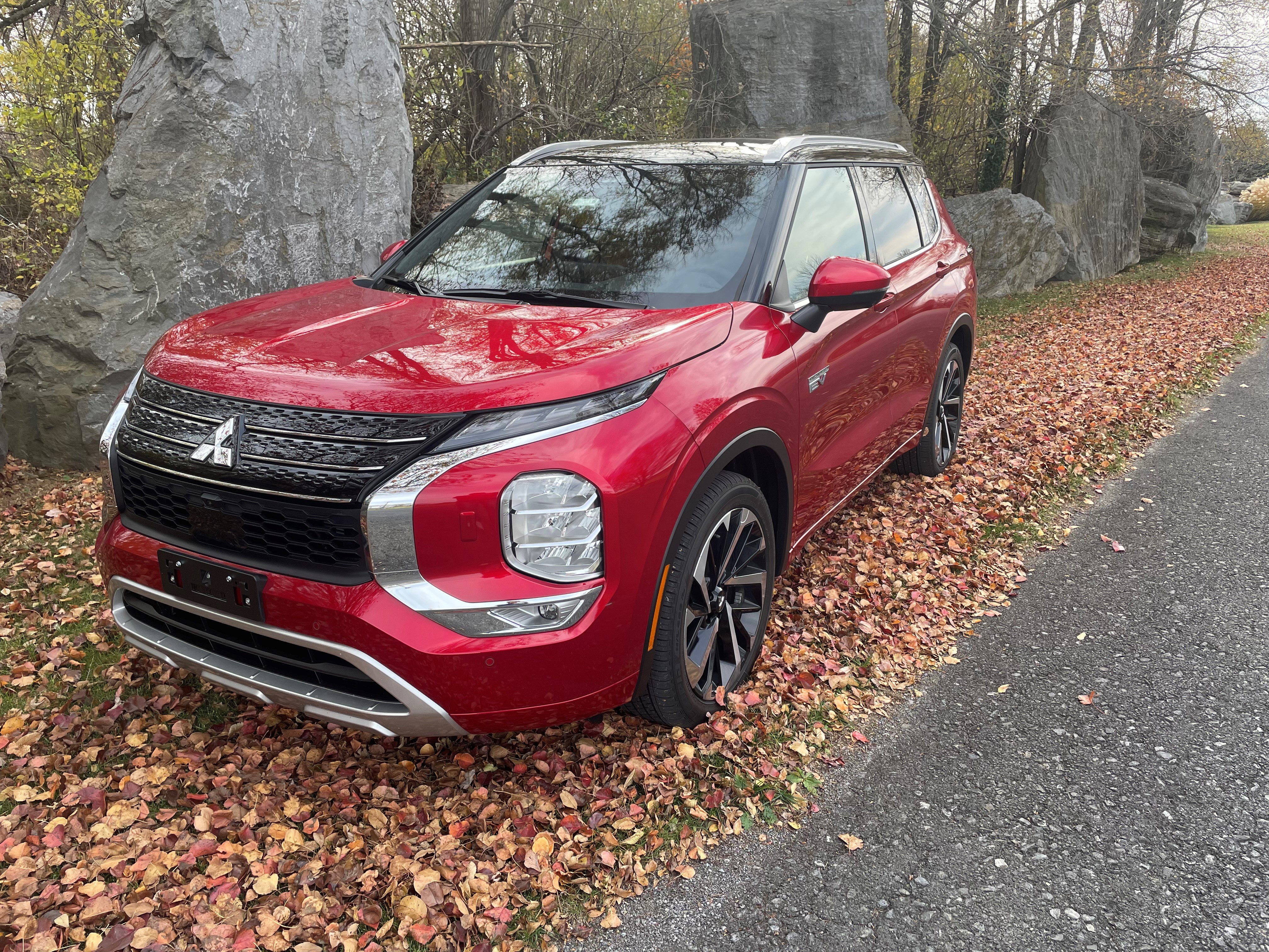 A red 2024 Mitsubishi PHEV Outlander beside a fall landscape