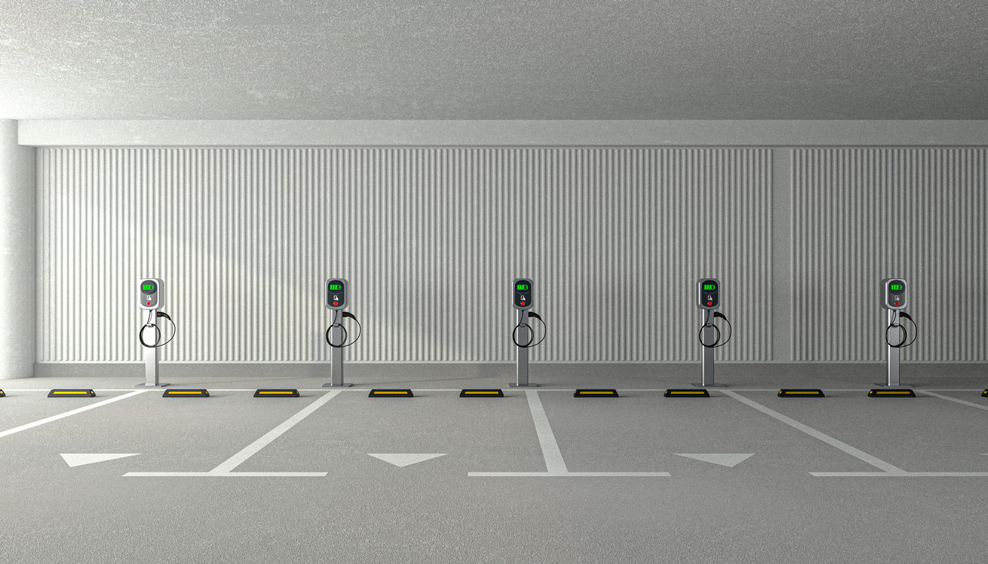 Row of electric vehicle chargers in front of parking spaces in a parking lot 