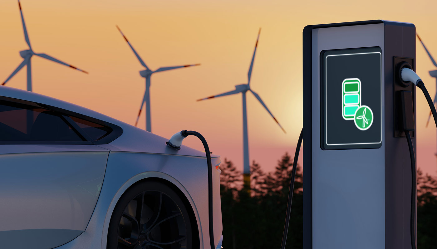 Electric vehicle charging at a charging station with wind turbines in the background