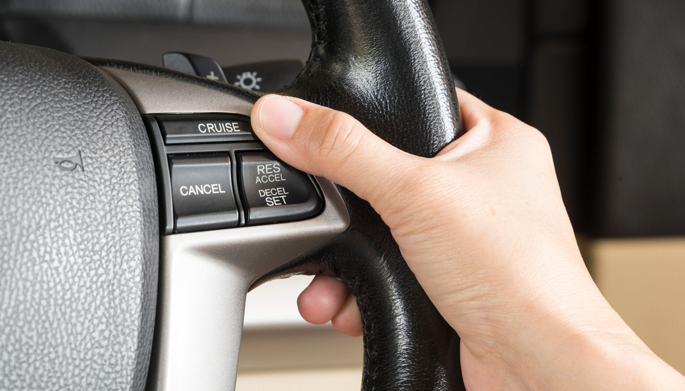 Hand on the steering wheel near adaptive cruise control