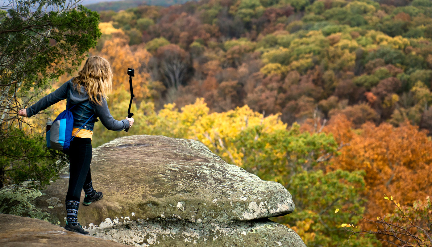 Woman standing on mountainous rock taking a photo