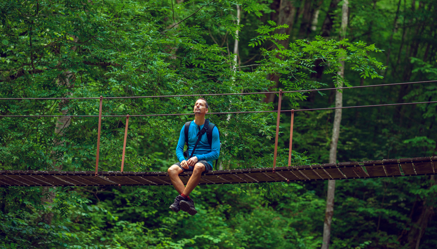 Man sitting in the middle of a swinging bridge