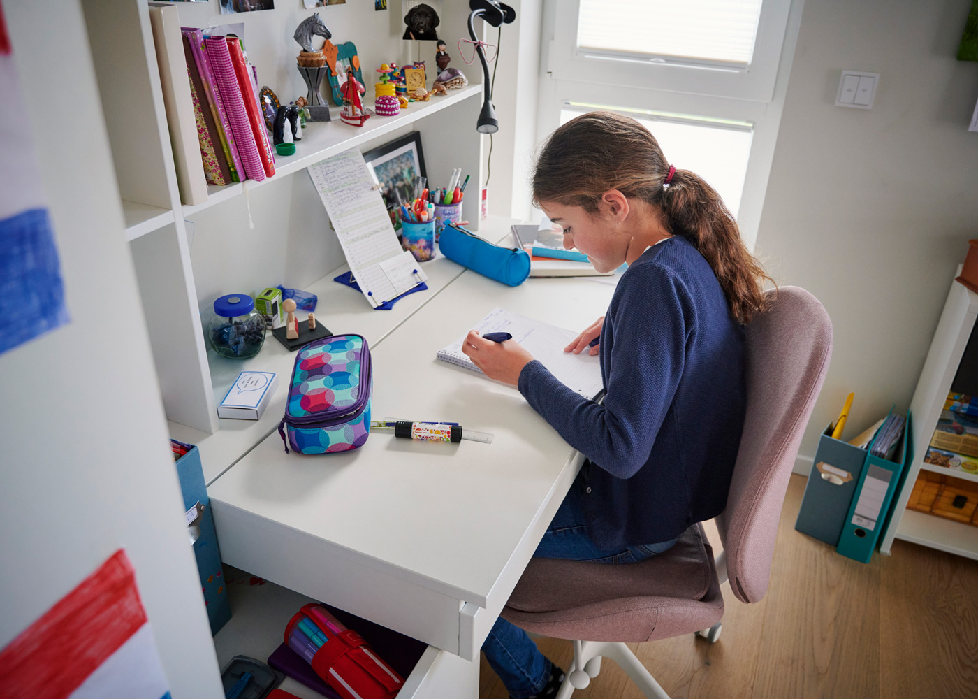 Girl doing homework in her room at a desk.