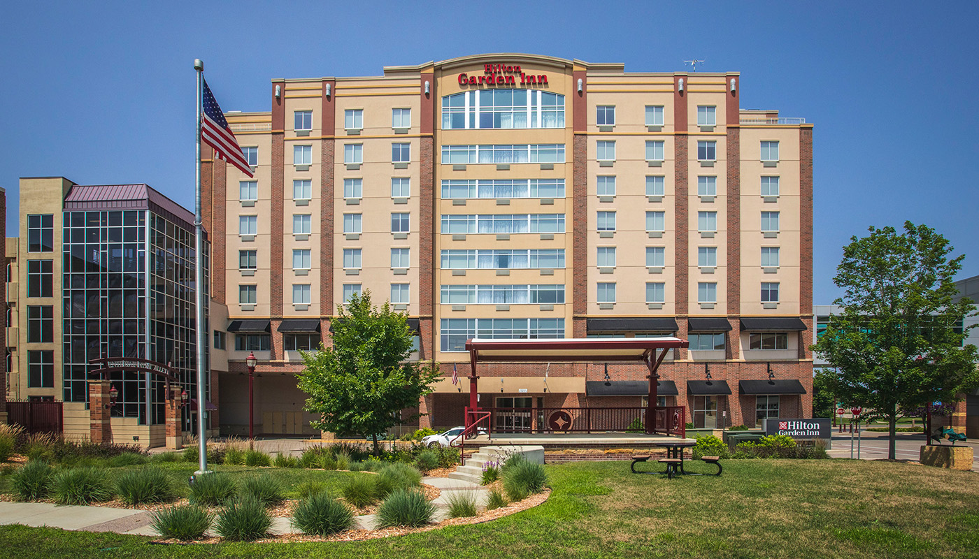 Exterior view of Hilton Garden Inn with American flag and landscaping in front